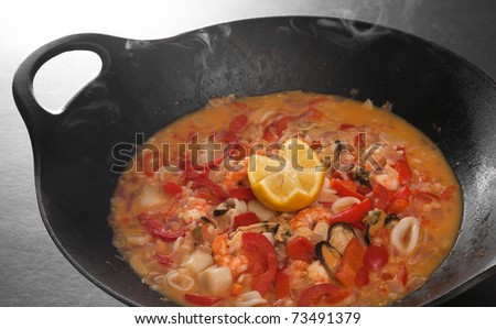freshly made steaming hot seafood paella in cast iron pot