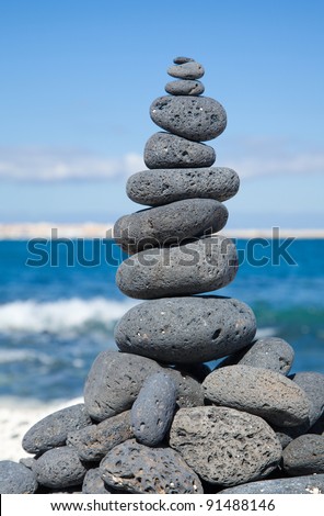 Christmas cairn - cairn built of black volcanic stones  in a shape of Christmas tree on a beach of black and white pebbles on Fuerteventura, Canary Islands, Spain