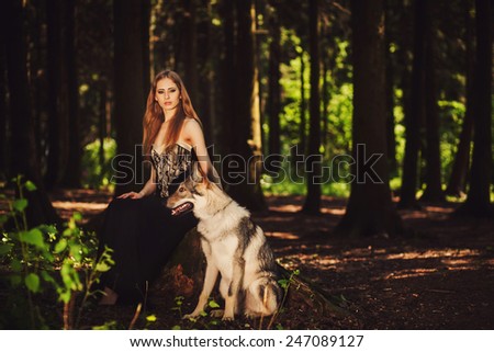 Pretty girl sitting with a dog in the dark forest