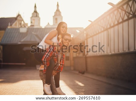 Happy loving couple. funny young man piggybacking his girlfriend. sunset
