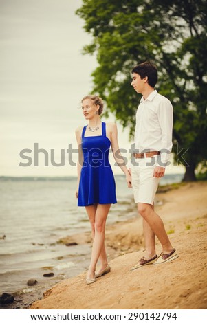 Romantic couple holding hands walking near lake. Man and woman in love.