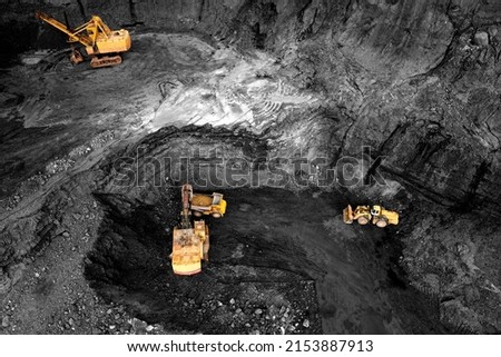 Coal mining in an open pit. Mining excavator loads coal in haul truck in quarry. Excavator digging in an open pit coal mine. Tipper truck hauling minerals from open-pit. Heavy machinery in opencast.  Imagine de stoc © 
