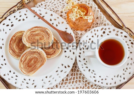Bolo de rolo (swiss roll, roll cake)  Brazilian dessert cup of tea vase on tray. Selective focus