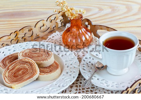 Bolo de rolo (swiss roll, roll cake)  Brazilian dessert cup of tea on tray with vase. Selective focus