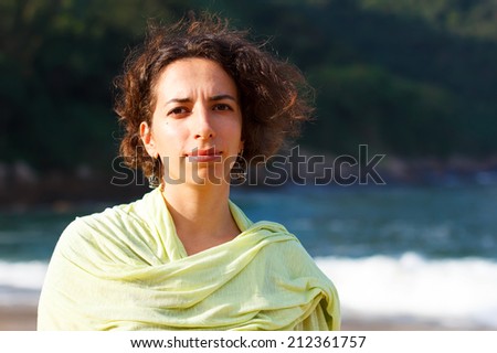 Young beautiful sad woman with curly hair outside on beach