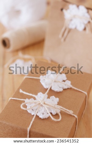 White crochet snowflakes for Christmas decoration of paper package and box gift. Selective focus