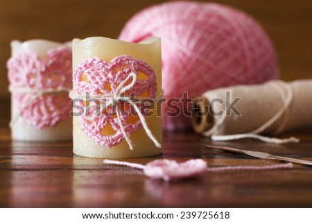 Two candle with  pink crochet handmade heart for Saint Valentine\'s day on wooden table. Selective focus