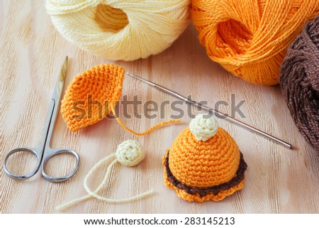 Making of handmade colorful crochet toys sweets with skein on wooden table. Selective focus