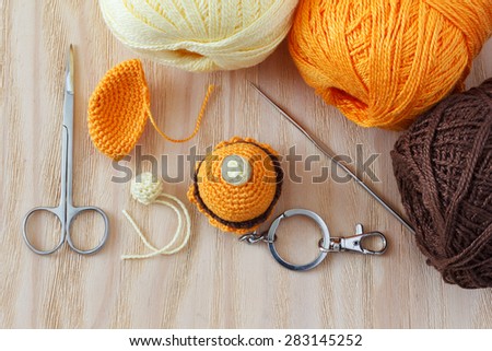 Making of handmade colorful crochet toys sweets (key ring) with skein on wooden table. Selective focus