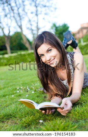 cute young girl lying on the grass, reading a book/ Girl reading book