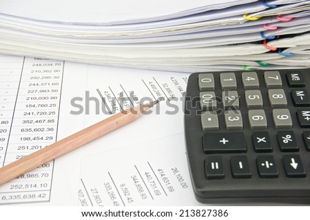 Stack of account with calculator and pencil place on statement and balance sheet.