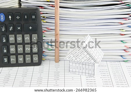 House and pencil in vertical on finance report with pile of paperwork as background.