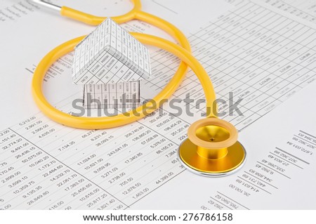 Yellow and gold stethoscope coil house place on finance account.