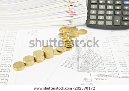 Bankruptcy of house and step pile of gold coins on balance sheet have calculator and pile of paperwork as background.