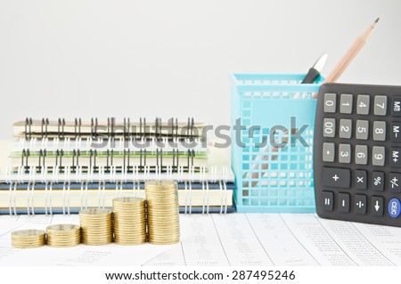 Step pile of gold coins on finance account with pile of notebook as background.