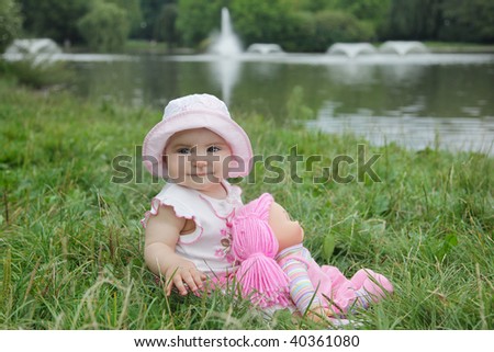 Cute baby girl with the doll in the park.