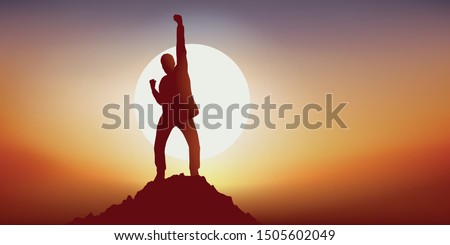 Concept of leadership with a man who expresses his joy by raising the point in a sign of victory by reaching the summit of a mountain