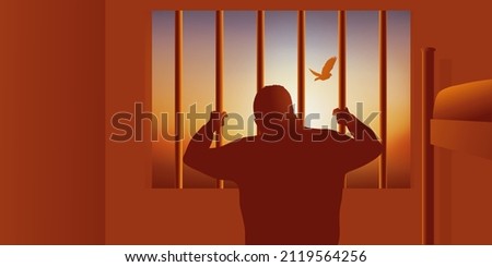 The prisoner’s concept enclosed in his cell, who looks at a bird flying behind the bars.
