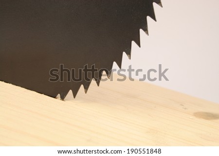 black saw blade sawing in a wooden board