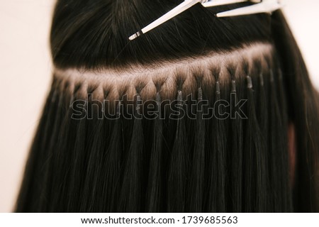 The hairdresser does hair extensions to a young girl in a beauty salon. Professional hair care. Close up of capsules and strands of grown hair Stockfoto © 
