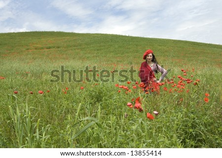 Spring explosion, cute girl with red hat and red scarf stands among red poppies