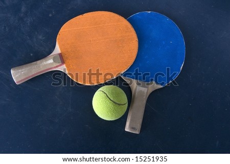 Ping pong racquets and tennis ball isolated on dark table