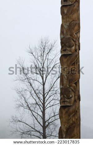 Traditional Gitxsan totem poles with lone tree behind, village of Kispiox, British Columbia, Canada