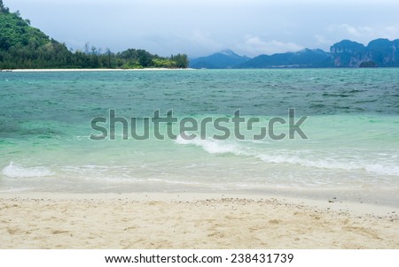 White wave of the sea on the sand beach and view from island and mountain