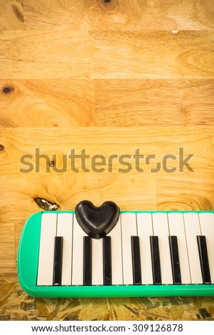 Still life with black heart and melodion on wooden background