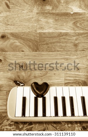 Still life with black heart and melodian on wooden background