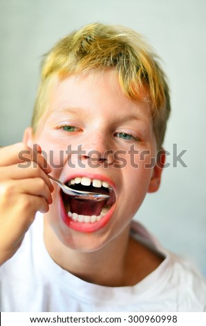 Eating red boy with spoon near open mouth