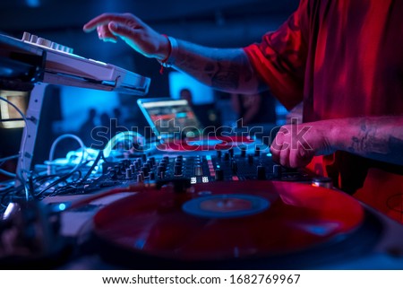 The DJ in the red T-shirt plays on the DJ equipment, play vinyl turntable, on the microbrand console using the controller. disco DJ. night life. atmosphere. club photo Сток-фото © 