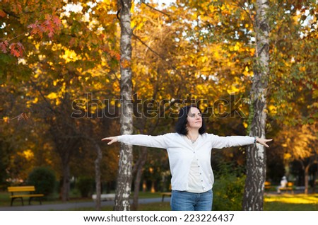 portrait of middle aged beautiful woman spreading her arms in park