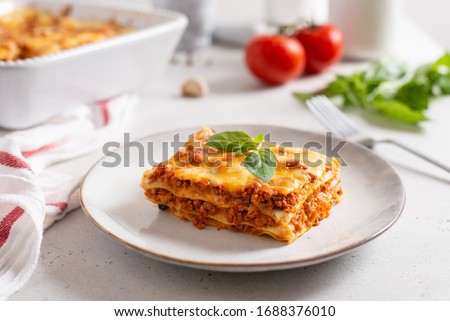 Piece of tasty hot lasagna served with a basil leaf on a gray plate. Italian cuisine, menu, recipe. Homemade meat lasagna. Close up, side view
