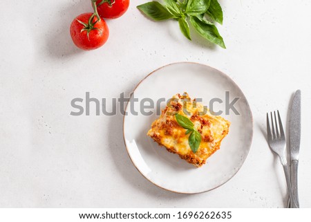Piece of tasty hot lasagna served with a basil leaf on a gray plate. Italian cuisine, menu, recipe. Homemade meat lasagna. Copy space for text, top view