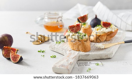 Fig, cream cheese and honey sandwiches. Canape or crostini with toasted baguette, cream cheese, figs and microgreen on a wooden board on white background. Italian recipe menu. Side view Photo stock © 