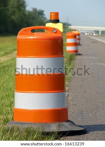 orange and white construction barrels set up on highway