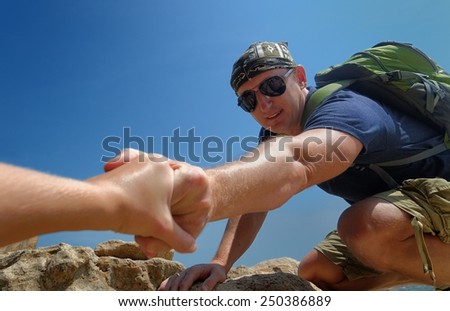 Tourist man helps someone to climb the mountain