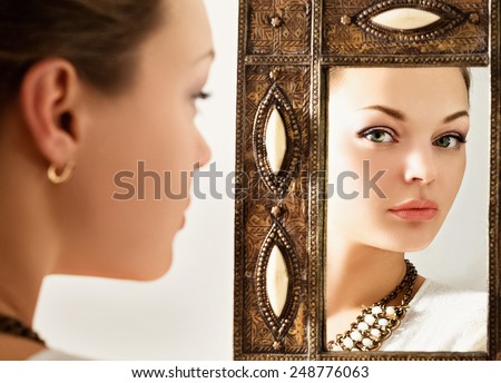 Portrait of a beautiful young woman with a mirror