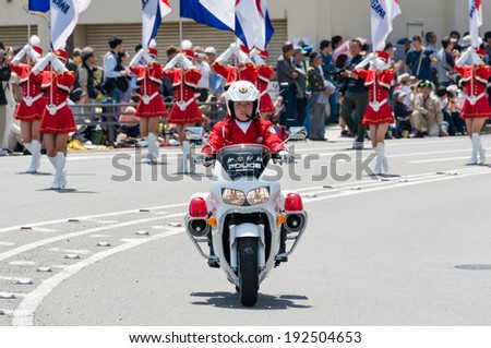 YOKOHAMA, JAPAN - MAY 3, 2014: A police woman on the motorcycle is leading the color guards of a brass band on the street in \