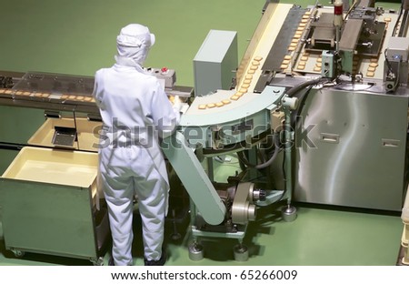 worker behind the conveyor in shop of confectionery factory