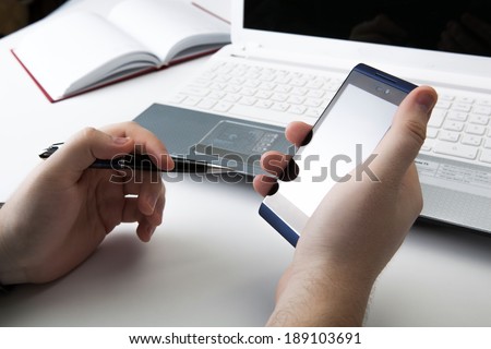 human fingers near the notebook keyboard and smartphone close-up