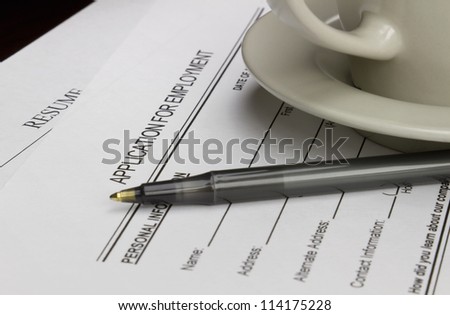 Blank employment application with resume, pen and coffee on desk.