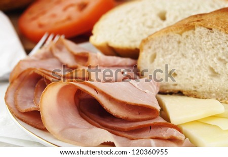 Delicious lunch time spread with ham, bread, cheese and tomatoes with silver fork