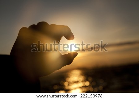 Catching the Sun at sunset time from a man\'s hand