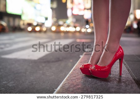 Lady legs with red high heel shoes at Time Square in New York City during night time.