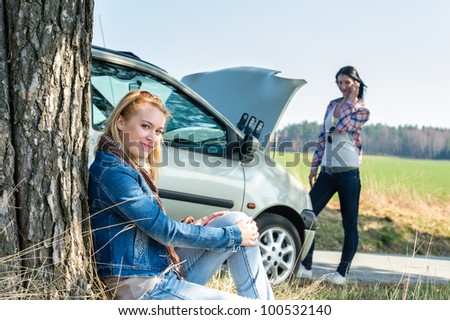 Car failure two young women waiting for help road assistance
