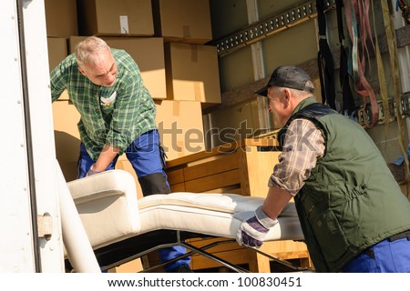 Two male movers putting furniture and boxes  in moving truck