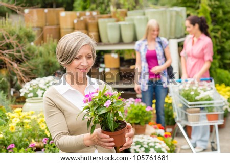 Senior lady shopping for flowers at garden center smiling
