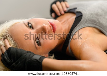 Female kick-boxer laying down on black plexiglass fitness studio
